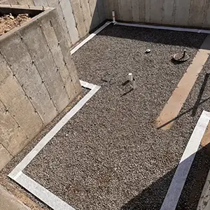 Passive radon system roughed in before the slab pour: clean gravel base, sealed perimeter expansion joint, and vent pipe stub-ups set in the foundation of a new Utah home