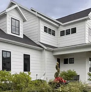 Radon mitigation system installed on a white modern farmhouse in Utah, with the vent pipe run flush against the siding and painted to blend in