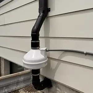Radon mitigation system installed on a white modern farmhouse in Utah, with the vent pipe run flush against the siding and painted to blend in